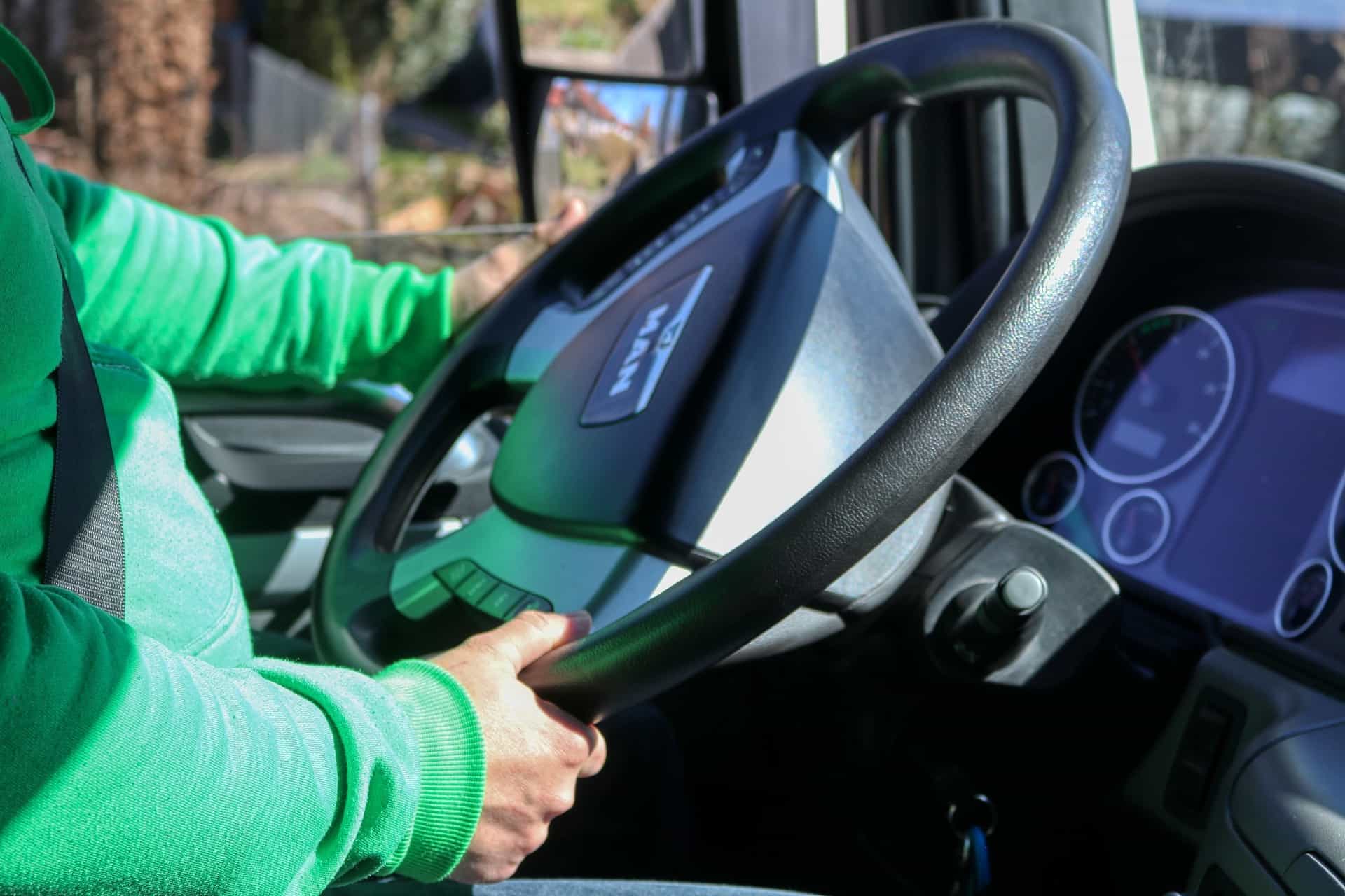 man wearing bright green jacket driving a semi-truck
