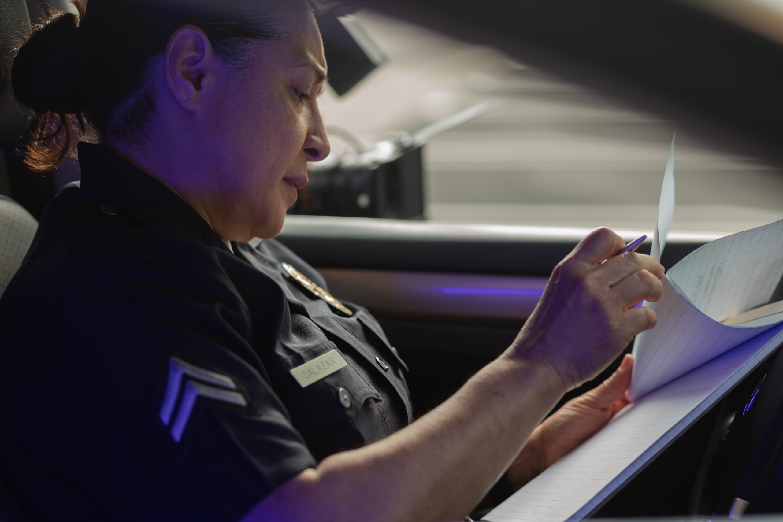 female officer looking at documents in police car