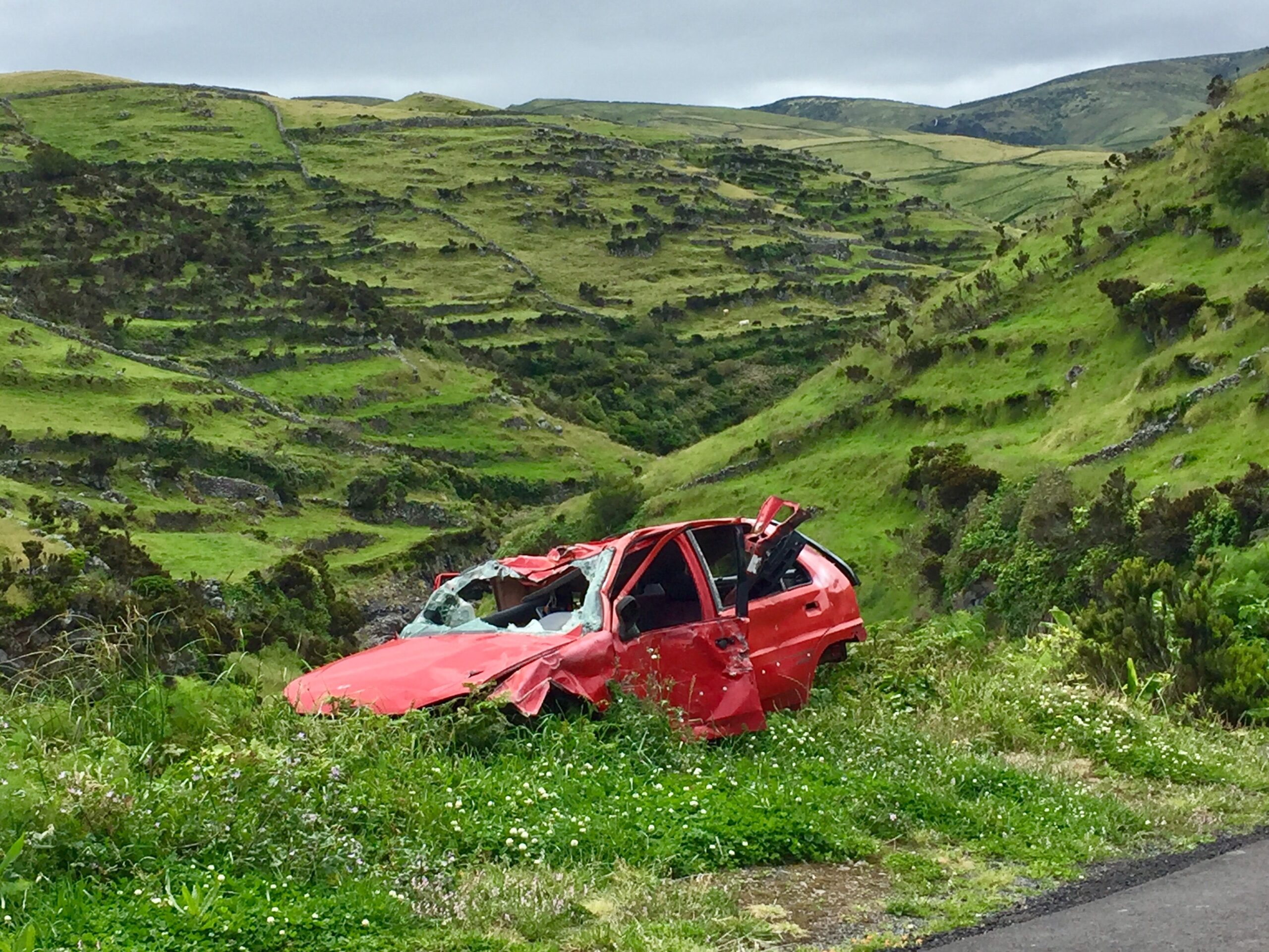 heavily damaged red vehicle on green hill