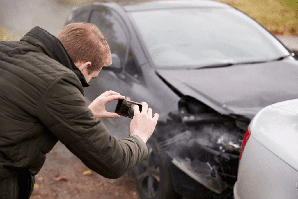A man taking a photo of a damaged car
