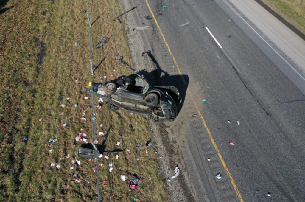 An aerial view of Lindsey’s car after the collision showing the vehicle on its left side and debris lying all around it.