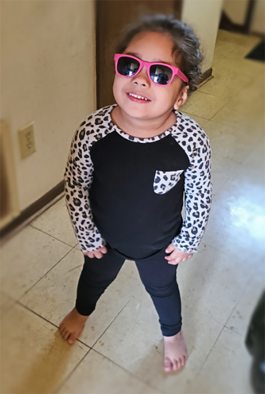 Norah in a leopard-print shirt and pink sunglasses