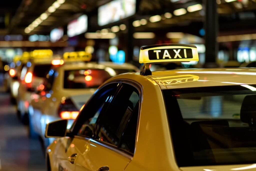 Multiple taxis in line on a busy street at night