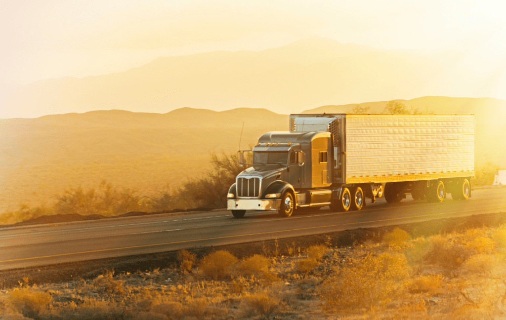 A truck driving along a highway during sunrise