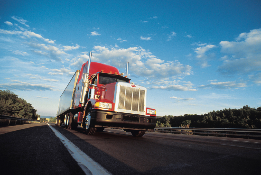 A semi-truck driving on highway on a bright day