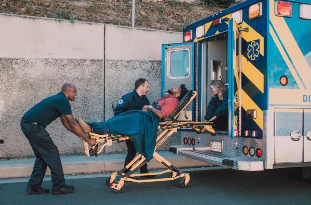 A person being on a stretcher being put inside an ambulance