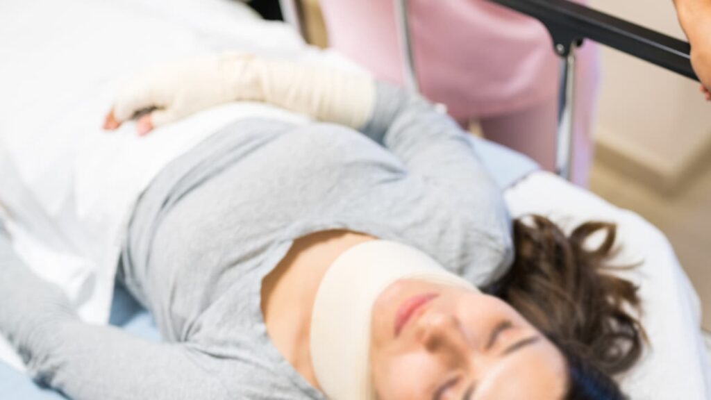 A woman wearing a neck brace and lying in a hospital bed