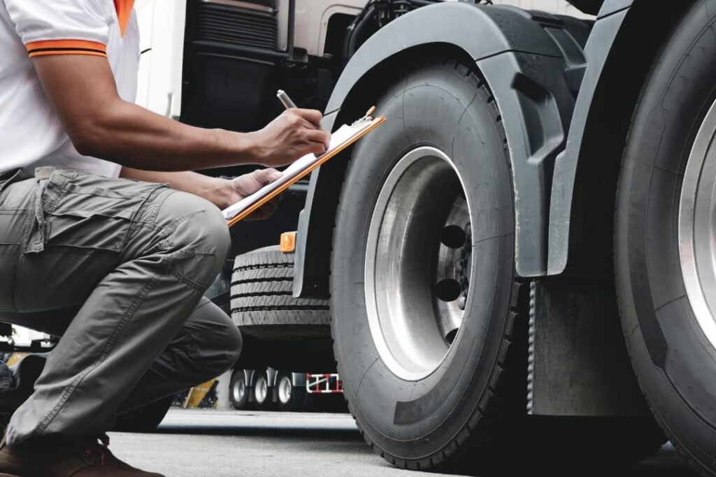 A man checking the wheels of an 18-wheeler truck