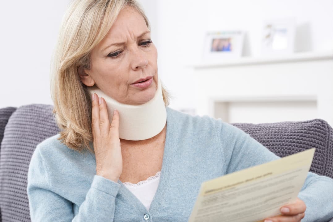 A person with a neck brace reading legal documents from a personal injury case