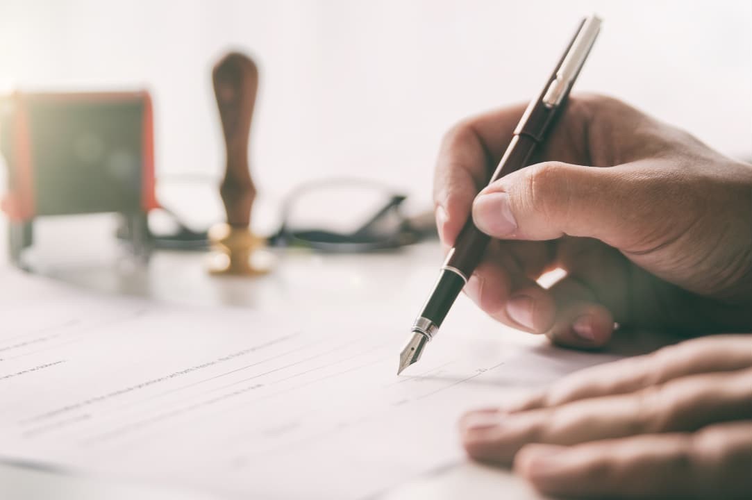 A person holding a pen signing a personal injury settlement document