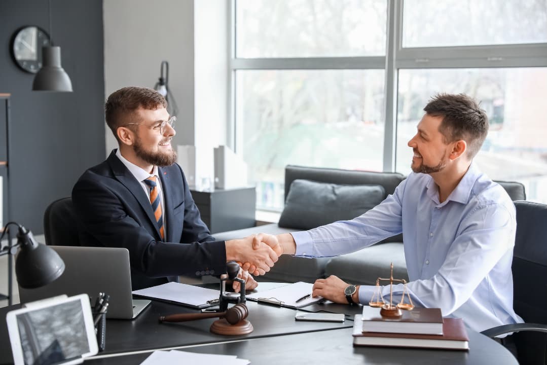 A lawyer and a client happily shaking hands after their meeting about personal injury case