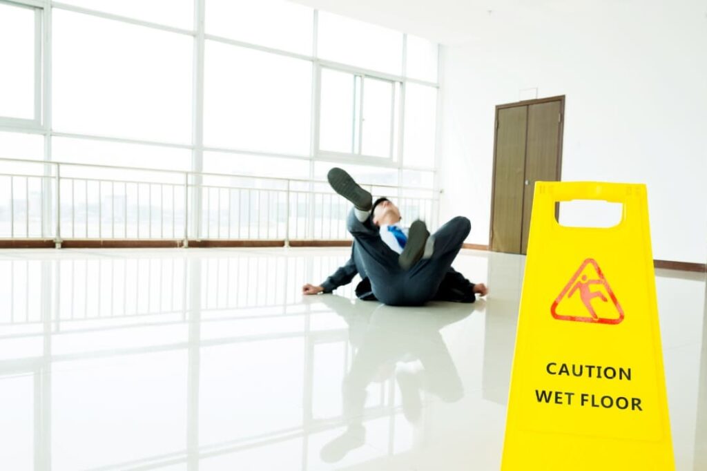 A man slipping and falling on a wet and slippery floor, losing balance and potentially experiencing an accident.