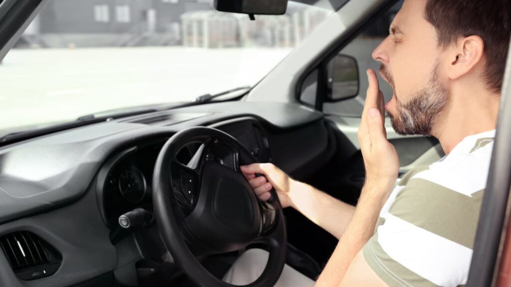 A man driving while drowsy poses a risk of an accident.