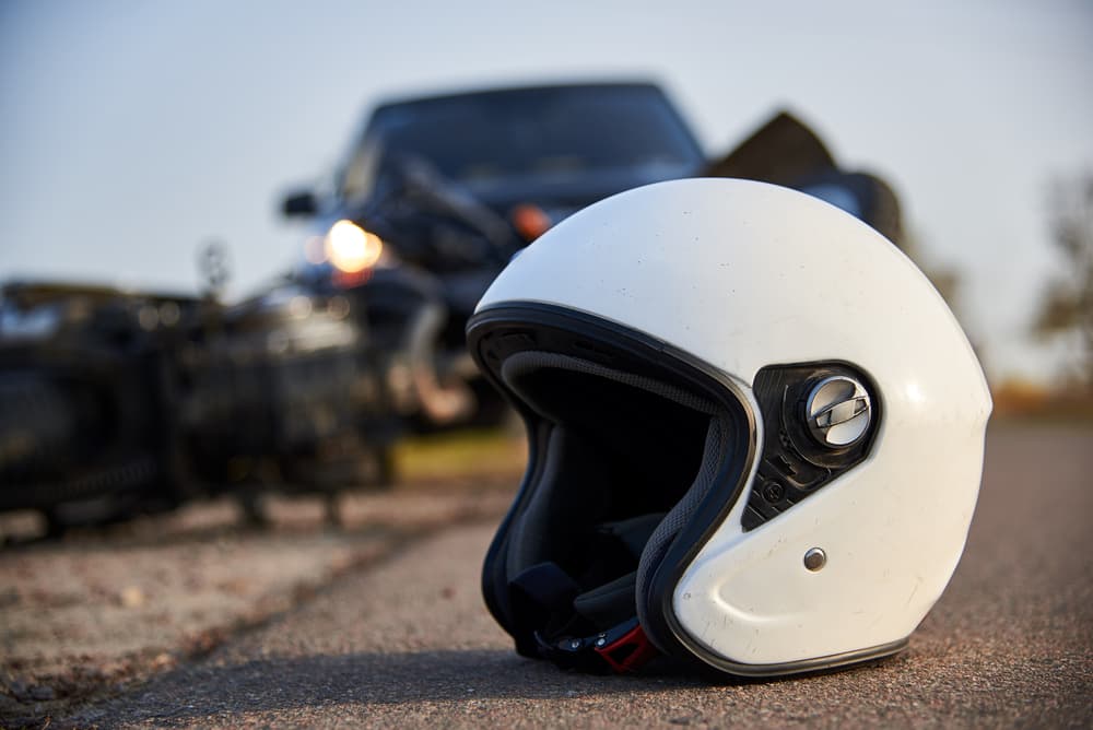 Helmet and damaged motorcycle lying on the asphalt after collision with a car