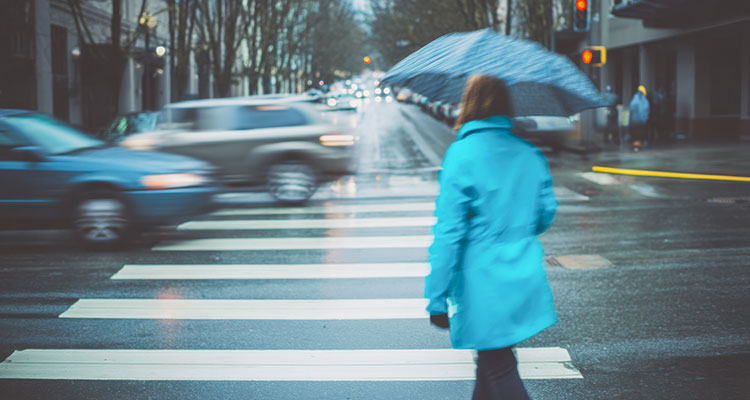 Pedestrian crossing a wet crosswalk in the rain, representing pedestrian accident risks in Gary