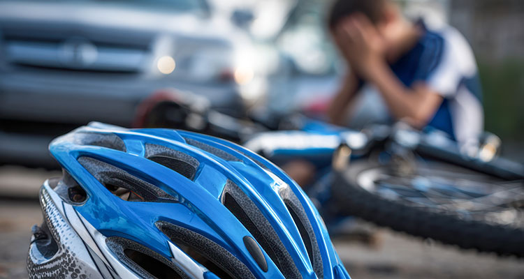 Bicycle helmet on the ground near an injured cyclist after a car crash
